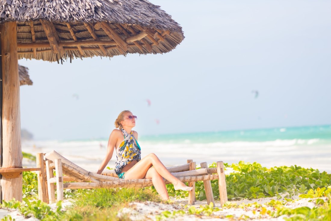 Zanzibar Woman sunbathing on tropical beach.